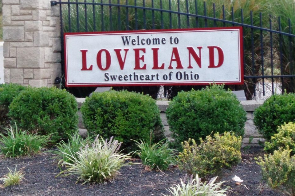 Loveland-Ohio - ABS Services Welcome sign for Loveland, Ohio, with the words 'Welcome to Loveland' and 'Sweetheart of Ohio' set against a white background with red lettering, surrounded by trimmed shrubs and landscaping.